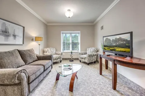 Room with a sofa, two armchairs, a television and large windows
