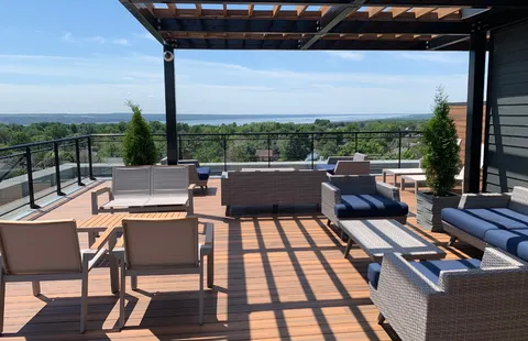 Rooftop terrace with sofas and a view over trees.