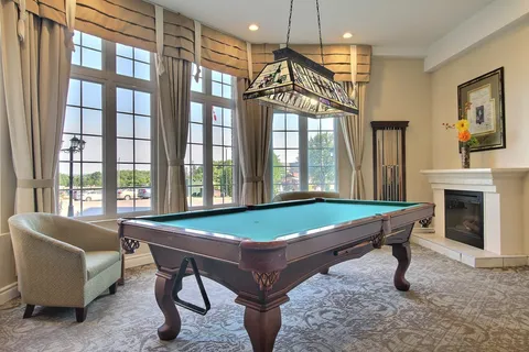 Games room with a billiards table, upholstered seating and a fireplace.