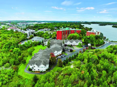 Aerial view of a residence surrounded by trees beside a lake