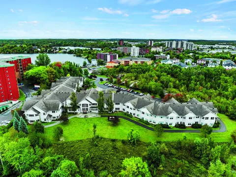 Aerial view of a white residence building beside trees and a broad lawn