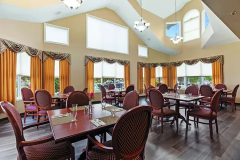 Dining room with burgundy chairs, set tables and high windows