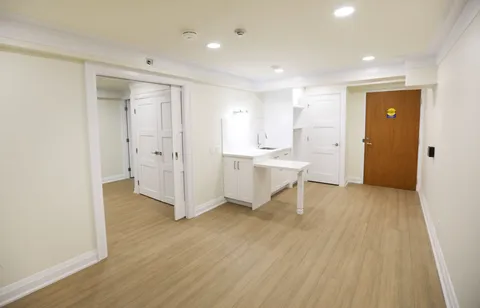 Kitchenette with white cabinetry beside a wooden entrance door