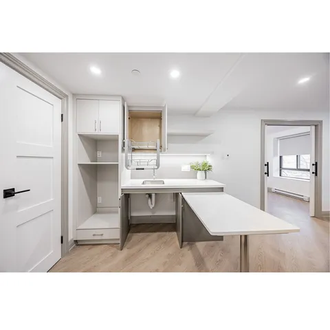 Kitchenette with white cabinets, a sink and open shelving