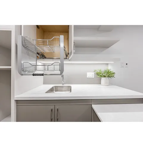 Kitchen counter with a sink beneath white cabinets and open shelving