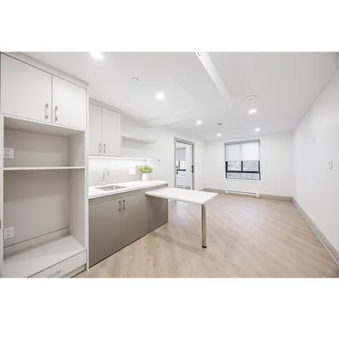 Unfurnished room with a kitchenette, open shelving and a window