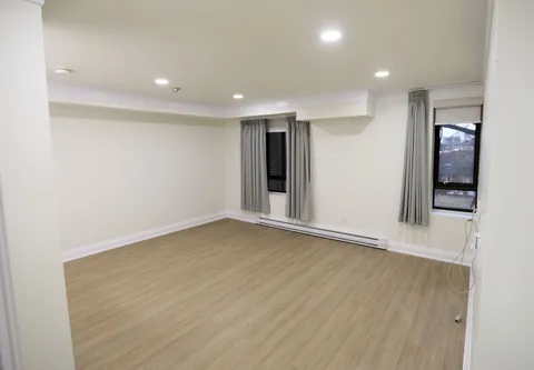 Unfurnished room with light wood flooring and two windows