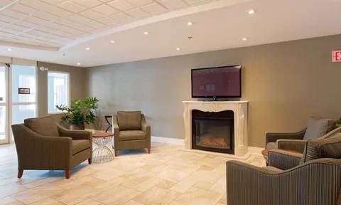 Lounge with armchairs around a fireplace.