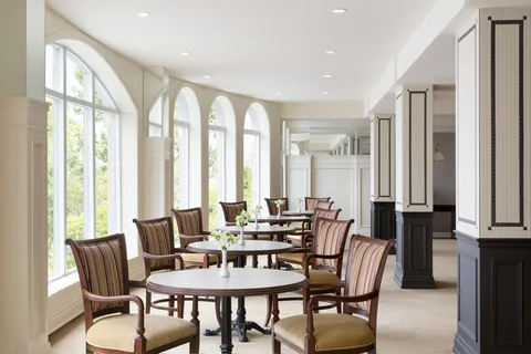 Bistro tables and chairs beside a row of arched windows.