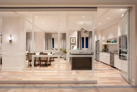 Craft kitchen with a long table and cabinets behind glass doors.