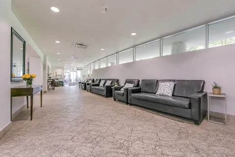 Rows of black sofas and side tables beside long interior windows