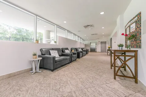 Bright corridor with black sofas, side tables and large interior windows