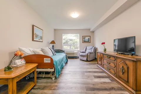 Bedroom with a bed, reclining chair, television and wooden cabinets