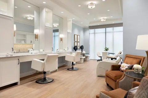 Salon with white styling chairs, mirrors and counters.
