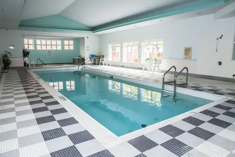 Indoor swimming pool with tiled decking and large windows.