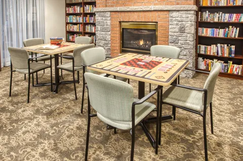 Library tables beside bookshelves and a fireplace.