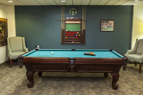 Billiards table beside armchairs and a scoreboard.