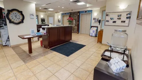 Reception counter beside seating and a carpeted lobby.