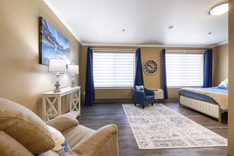 Bedroom with blue curtains, armchairs, a rug and a bed