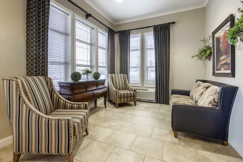 Sitting area with striped armchairs, a loveseat and tall windows
