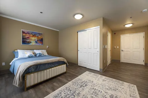 Bedroom with a bed, white closet doors and a sailboat painting