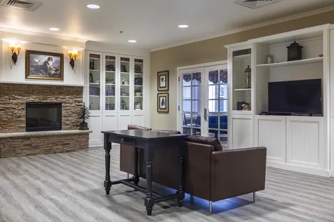 Room with leather seating, a stone fireplace, bookshelves and a television