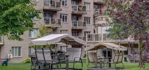 Patio with covered swing seats and tables beside the building.