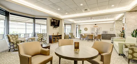 Lounge with armchairs, small tables and large windows.