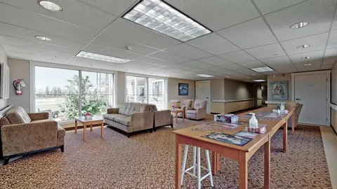 Windowed seating area with sofas, armchairs and tables holding jigsaw puzzles