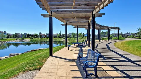 Paved path and benches beneath pergolas beside a pond