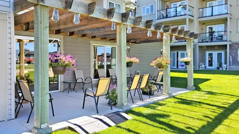 Patio with outdoor chairs beneath a wooden pergola beside the building