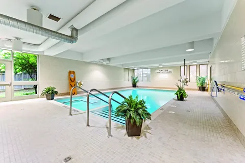 Indoor swimming pool with handrails and potted plants