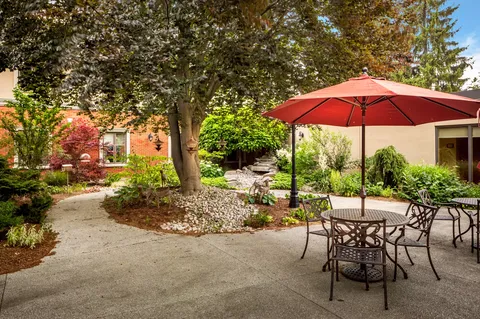 Garden patio with a red umbrella, chairs and planted beds