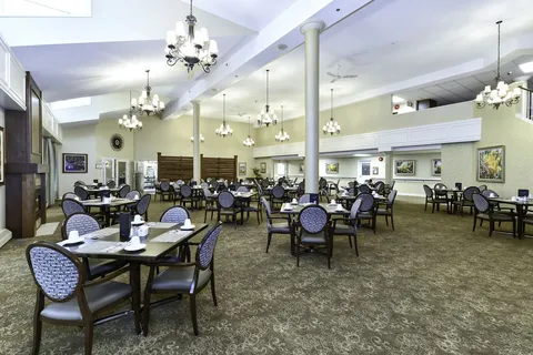 Dining room with round set tables beneath chandeliers.