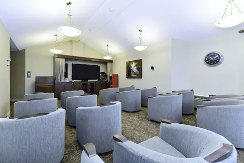 Screening room with rows of upholstered chairs and television.