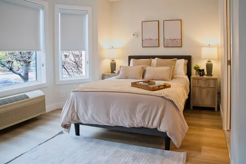 Bedroom with a bed, nightstands and two windows.