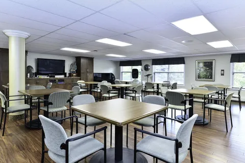 Common room with tables, chairs and wall televisions.