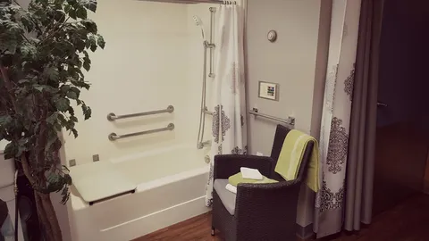 Accessible bathing area with a folding shower seat, grab bars and a chair