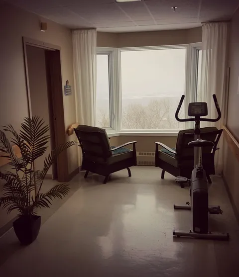 Exercise bike and two chairs beside a large window