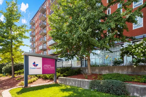 Residence building with balconies beside trees and a freestanding sign