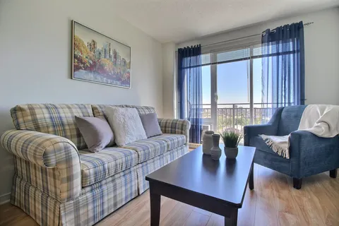 Sitting area with a plaid sofa, armchair and balcony door