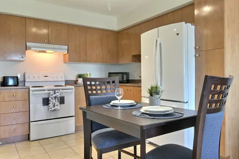Kitchen with wooden cupboards, appliances and a small dining table