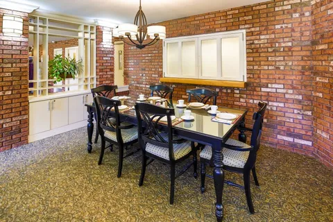 Dining room with a long table, black chairs and a brick wall