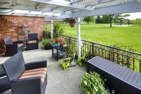 Patio with wicker chairs, potted plants and a white pergola