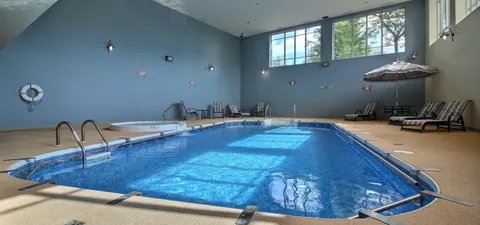 Indoor swimming pool with lounge chairs and high windows