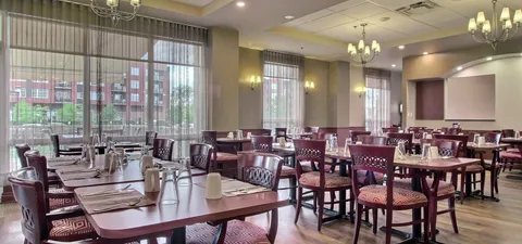 Dining room with wooden tables, burgundy chairs and large windows