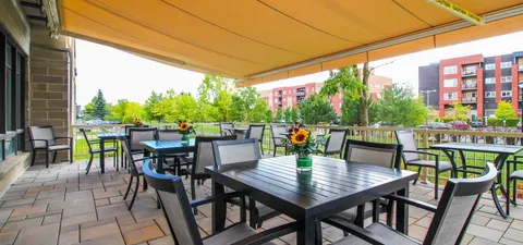 Patio dining tables and chairs beneath a yellow awning