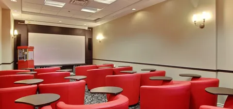 Screening room with red chairs facing a blank screen