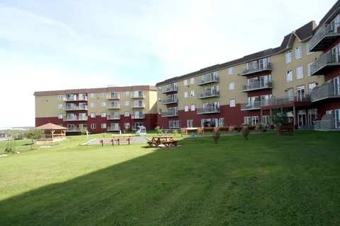 Residence with balconies beside a lawn, picnic tables and a gazebo