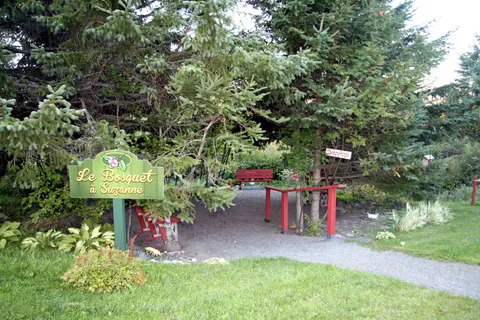 Wooded garden path with red benches, a handrail and a green sign